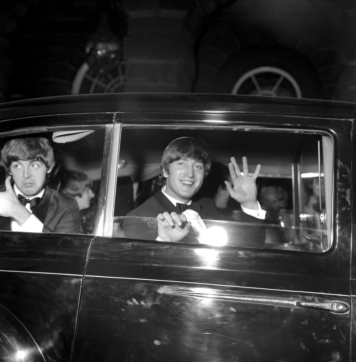 ohn Lennon et Paul McCartney saluent de la voiture sur le chemin de la première. juillet 1964  (Image : Mirrorpix)