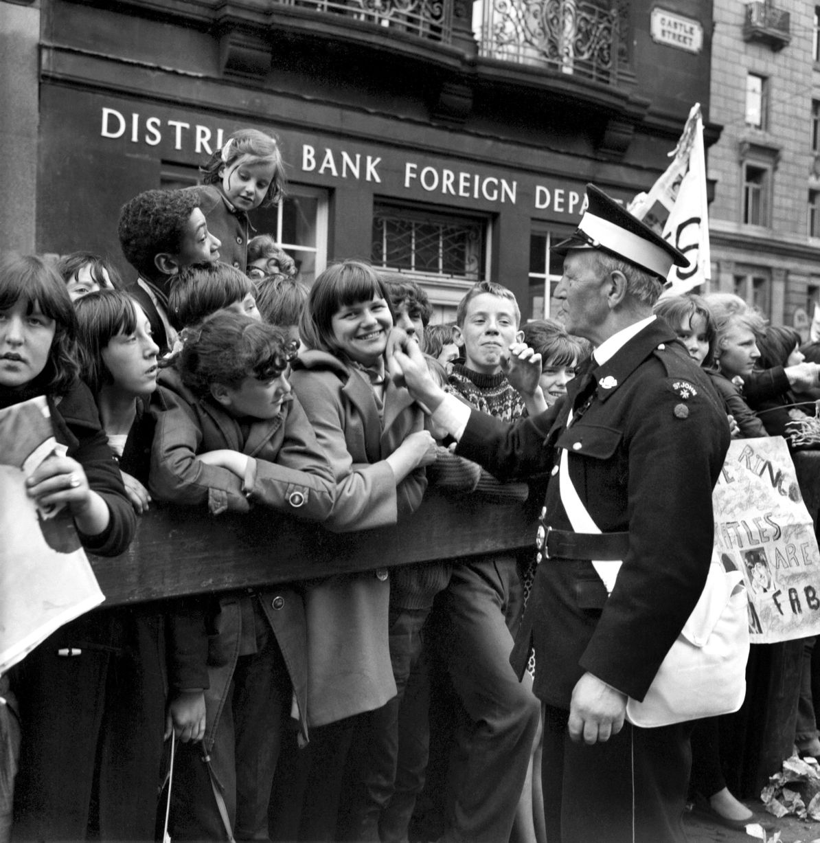 Le travailleur de l'Ambulance Saint-Jean vérifie le bien-être des fans qui font la queue dans les rues de Liverpool avant la première du film des Beatles A Hard Day's Night. juillet 1964