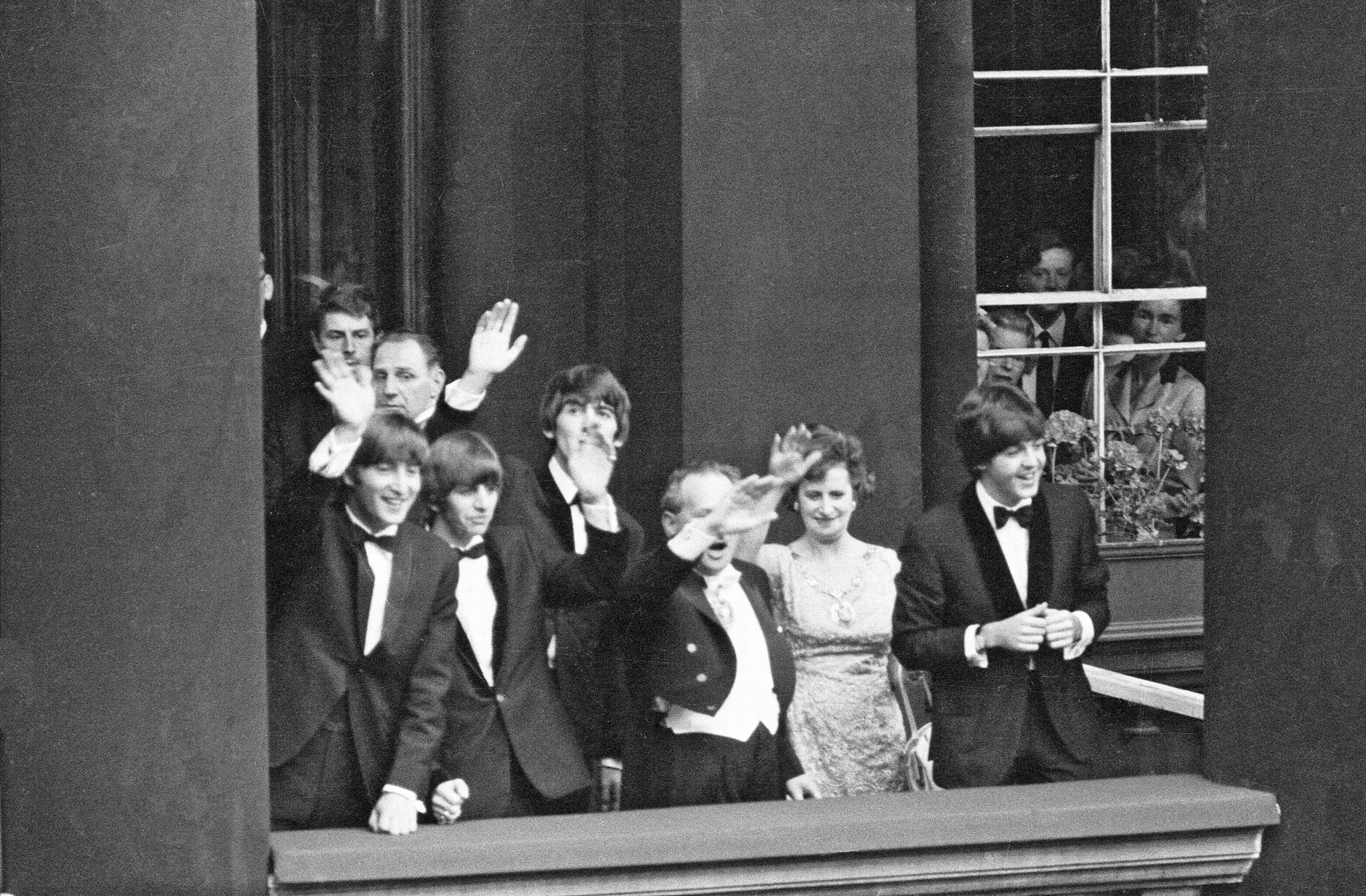 À Liverpool pour la première de A Hard Day's Night, John Lennon, Paul McCartney, Ringo Starr et George Harrison saluent depuis un balcon une foule de fans. juillet 1964
