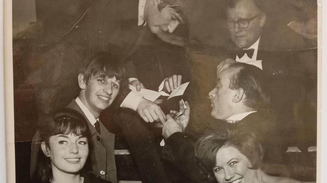John Lennon signe un autographe lors du Royal Variety Performance de 1963 avec Ringo Starr au premier plan (The Beatles Shop/PA)