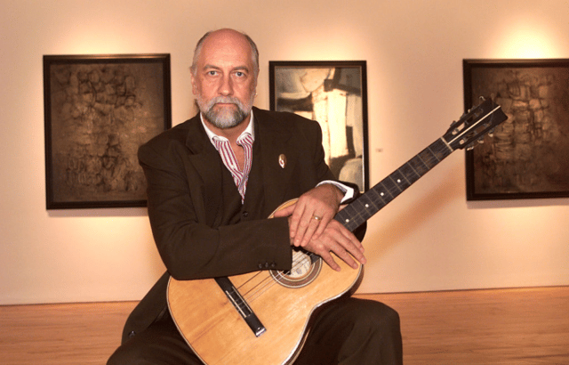 Mick Fleetwood tenant la première guitare de Stuart Sutcliffe lors d'une conférence de presse pour dévoiler les œuvres d'art et les souvenirs de Sutcliffe à la Westwood Gallery à New York.